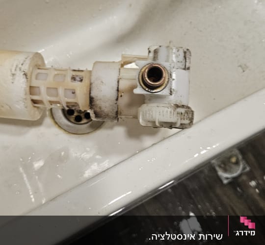 חלקי צנרת בכיור עם מים על הרצפה